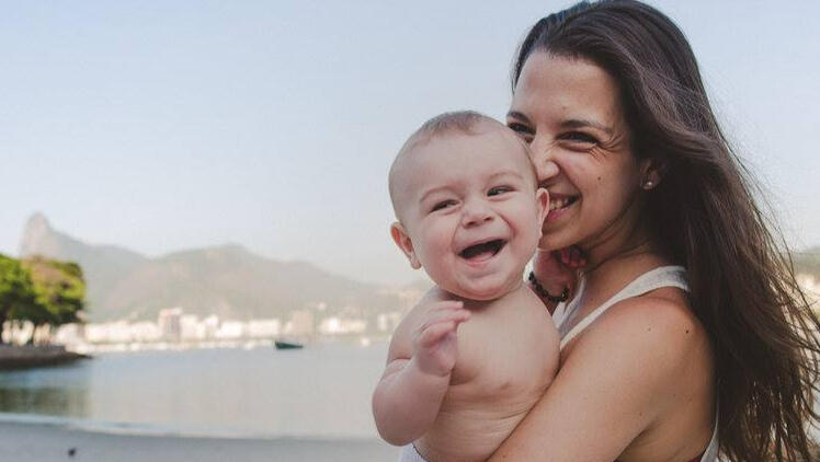 Camila-Clarke-in-Rio Family Photographer and mum, Camila, holding her baby in a beach in Rio de Janeiro